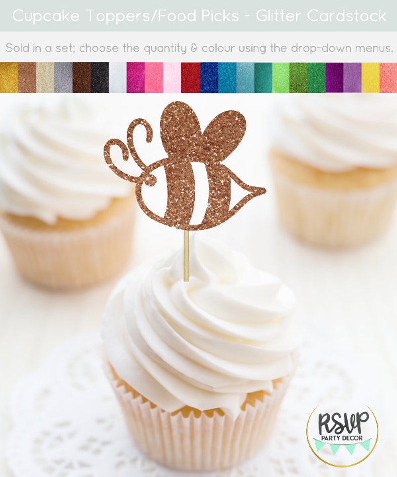 May include: Gold glitter cupcake topper shaped like a bee. The bee has white stripes and a brown body. The topper is on a cupcake with white frosting. The cupcake is on a white doily. The text "RSUP PARTY DECOR" is in the lower right corner of the image.