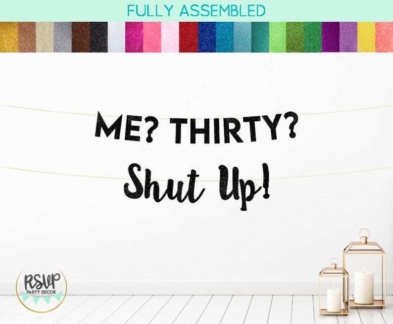 Puede incluir: Pancarta negra de purpurina con el texto "ME? THIRTY? SHUT UP!" colgada en una pared blanca. La pancarta est&aacute; hecha de letras individuales y est&aacute; enhebrada con una cuerda dorada.