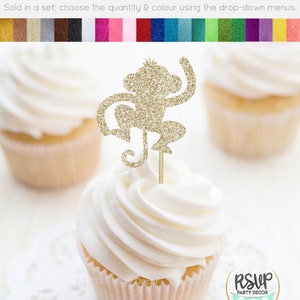 K&ouml;nnte beinhalten: Goldener Glitzer-Affen-Cupcake-Topper. Der Affe sitzt mit einem erhobenen Arm. Der Topper befindet sich auf einem wei&szlig;en Cupcake mit wei&szlig;em Frosting.