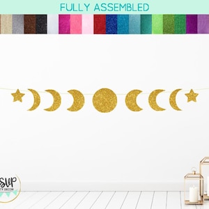May include: Gold glitter moon and star banner with the text "RSVP Party Decor" in the bottom left corner. The banner is hanging on a white wall.