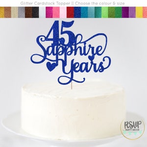 May include: Blue glitter cardstock cake topper with the text "45 Sapphire Years" and two small hearts.