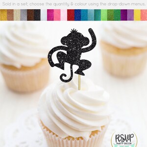 K&ouml;nnte beinhalten: Schwarzer Glitzer-Affen-Cupcake-Topper. Der Topper befindet sich auf einem wei&szlig;en Cupcake mit braunem Cupcake-Papier. Der Cupcake steht auf einer wei&szlig;en Spitze. Der Text "RSVP Party Decor" befindet sich unten rechts im Bild.