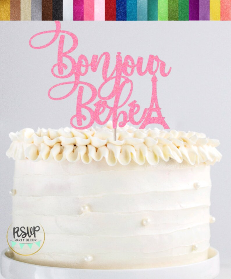 May include: Pink glitter cake topper with the text "Bonjour Bebe" and a small Eiffel Tower design.