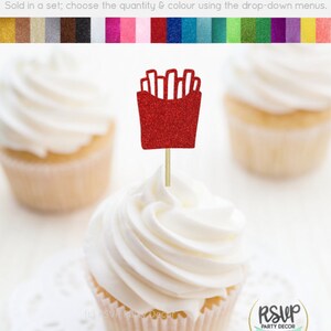 May include: Red glitter cupcake topper shaped like a box of french fries. The topper is on a wooden stick and is ready to be placed on a cupcake. The text "RSVP Party Decor" is visible in the bottom right corner of the image.