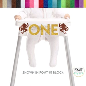 May include: Gold glitter "ONE" high chair banner with two brown monkey silhouettes. Shown in font #1 block.
