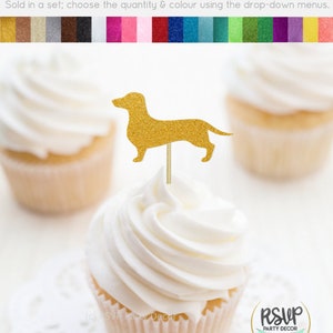 May include: Gold glitter dachshund cupcake topper. The topper is on a white cupcake with white frosting. The cupcake is on a white doily. The text "RSVP Party Decor" is visible in the bottom left corner of the image. The text "RSVP Party Decor" is visible in the bottom right corner of the image.