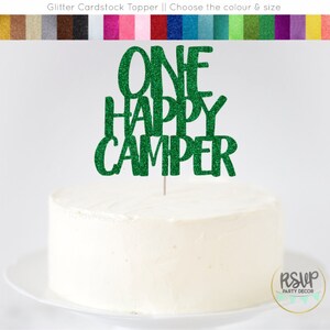 May include: Green glitter cardstock cake topper with the text "ONE HAPPY CAMPER".