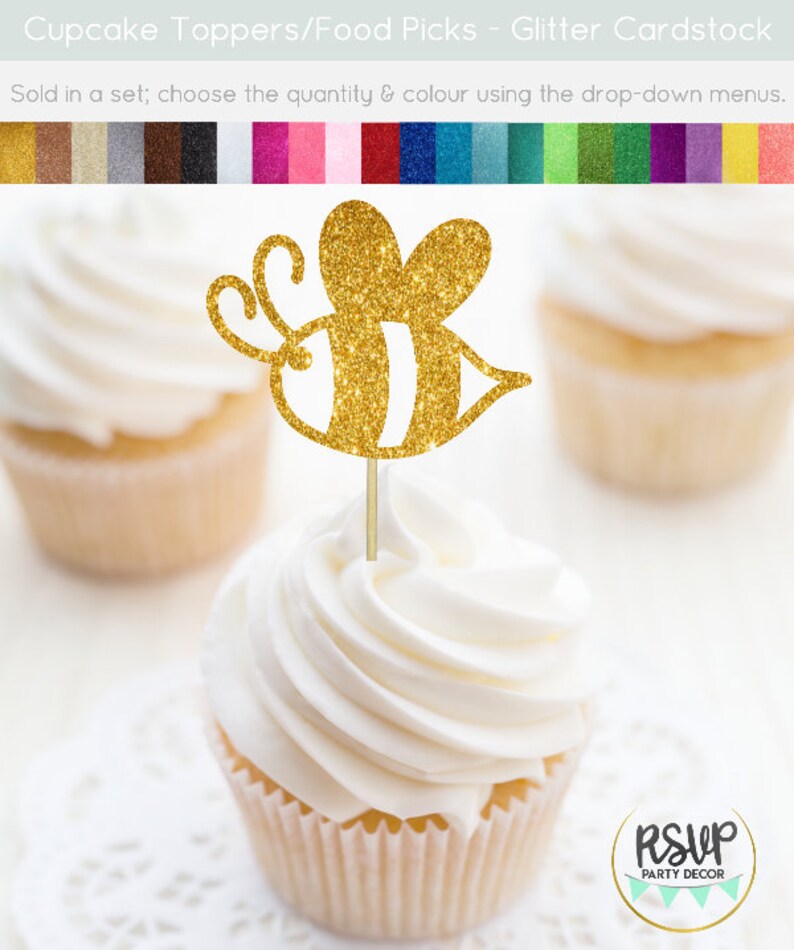 May include: Gold glitter bee cupcake topper. The bee has black and white stripes. The topper is on a white cupcake with white frosting. The cupcake is on a white doily. The text "RSUP PARTY DECOR" is in the lower right corner of the image.