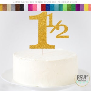 May include: Gold glitter cardstock cake topper with the number "1 1/2" for a birthday party.