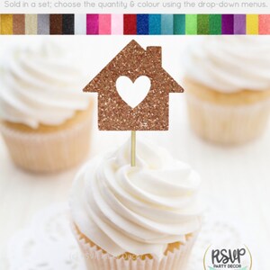 May include: A cupcake topper featuring a glitter-covered house with a heart cut-out. The topper is made of cardstock and is perfect for adding a touch of whimsy to cupcakes.