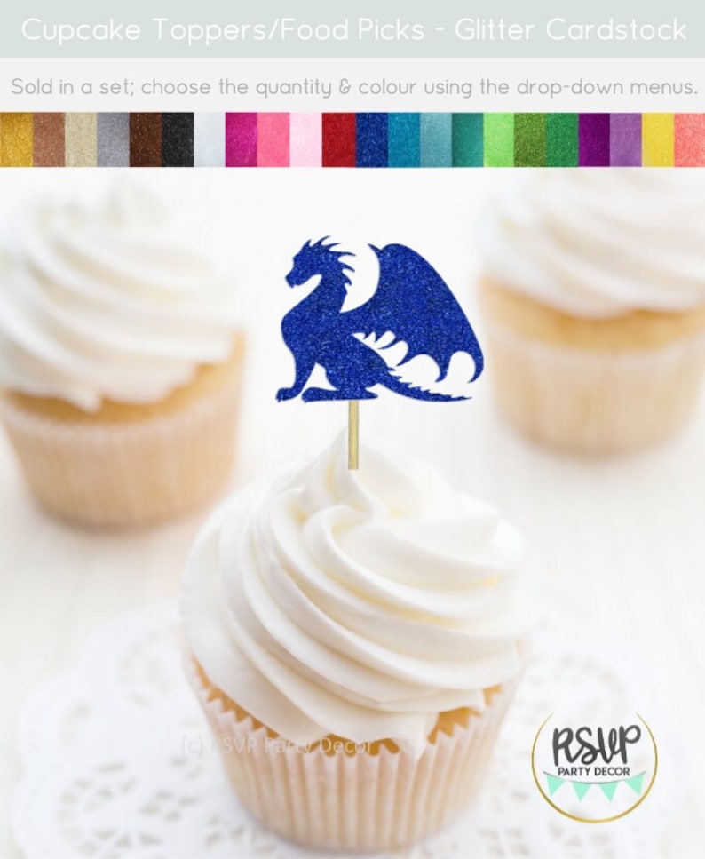May include: Blue glitter dragon cupcake topper. The dragon is sitting on its haunches with its wings spread out. The topper is on a white cupcake with white frosting. The cupcake is on a white doily. The text "RSVP Party Decor" is on a gold circle sticker.