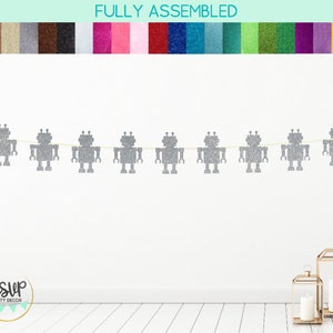 May include: A silver glitter robot party banner with the text "FULLY ASSEMBLED" at the top. The banner is strung with a white string and features eight robots.