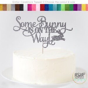 May include: Silver glitter cake topper with the text "Some Bunny is on the Way" and a bunny silhouette.