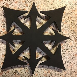 Peut inclure: Décoration murale noire en forme d'étoile avec un motif géométrique. La pièce d'art est faite d'un matériau solide et a une surface plane.
