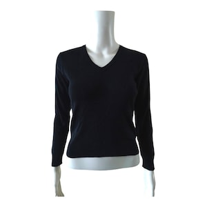 May include: A solid black long-sleeve jumper featuring a V-neckline and ribbed cuffs at the wrists and hem. The garment is displayed on a mannequin torso, showcasing a fitted silhouette with a clean, plain knit texture throughout the entire piece.