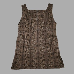 Könnte beinhalten: Ein ärmelloses Kleid mit einem braun-schwarzen Schlangenmuster. Das Kleidungsstück hat einen eckigen Ausschnitt, ein tailliertes Oberteil mit einer definierten Taille und einen sichtbaren vertikalen Reißverschluss im oberen Brustbereich.