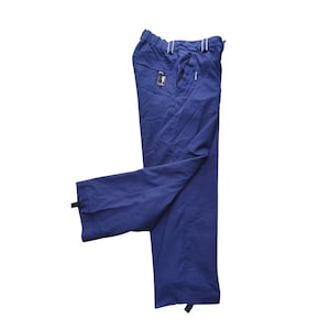 Op de afbeelding: Een donkerblauwe broek met een elastische tailleband met witte gestreepte details, zijzakken met ritssluiting en verstelbare zwarte treklipjes aan de onderkant van elke broekspijp voor een aanpasbare pasvorm en functioneel ontwerp.