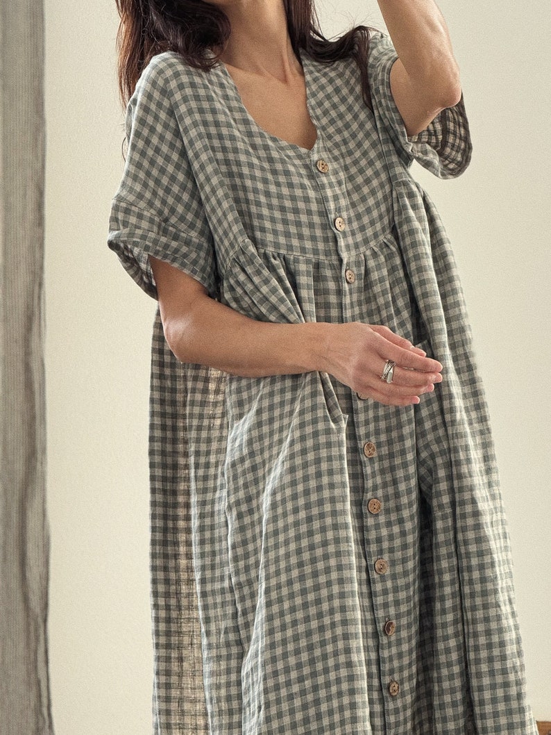 Pu&ograve; includere: Un vestito a quadri vichy verde e bianco con bottoni sul davanti e maniche corte.