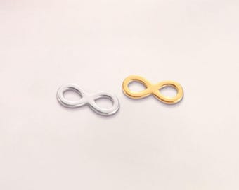 Könnte beinhalten: Zwei Unendlichkeitszeichen-Anhänger, einer silberfarben und einer goldfarben, werden vor einem hellen Hintergrund gezeigt. Die Anhänger sind klein und haben ein schlichtes Design. Das Bild ist gut beleuchtet und hebt die Details der Anhänger hervor.