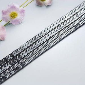 May include: A strand of black hematite beads with a wavy, textured surface. The beads are arranged in a straight line and are approximately 8mm in diameter.