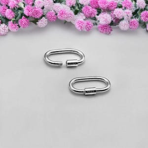 Puede incluir: Dos cierres ovalados de plata con cierre de tornillo. Los cierres están marcados con "S925" en el lateral.