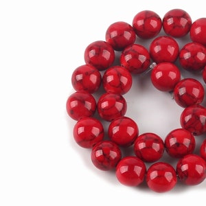 Könnte beinhalten: Eine Strähne roter und schwarzer marmorierter runder Perlen. Die Perlen haben einen Durchmesser von etwa 10 mm.