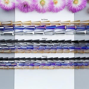 May include: Three rows of iridescent glass beads in various sizes. The top row is labelled "6x12mm", the middle row is labelled "4x8mm", and the bottom row is labelled "3x6mm".