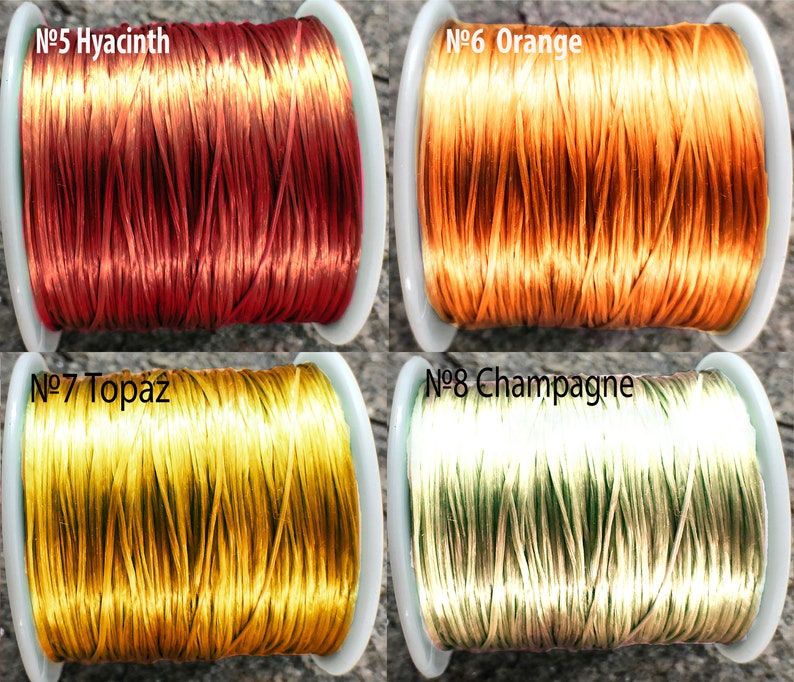 May include: Four spools of thread in different colors: red, orange, yellow, and cream. The spools are labeled with numbers and color names: No. 5 Hyacinth, No. 6 Orange, No. 7 Topaz, and No. 8 Champagne.