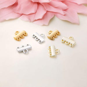 May include: Six gold and silver metal jewelry clasps with multiple loops. The clasps are designed to connect multiple strands of beads or chains.