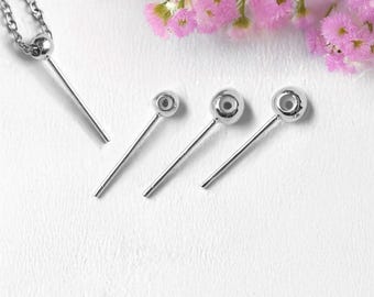 May include: A silver necklace with a pendant and three matching silver hair pins. The pendant is a small silver ball attached to a straight silver bar. The hair pins have a silver ball on top of a straight silver bar. Pink flowers are in the background.