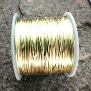 Pode incluir: Um carretel de cordão elástico dourado e verde.