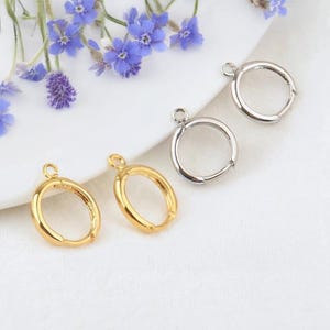 May include: Two pairs of hoop earring findings, one pair is gold and the other is silver. The findings have a small loop at the top for attaching a charm or pendant.