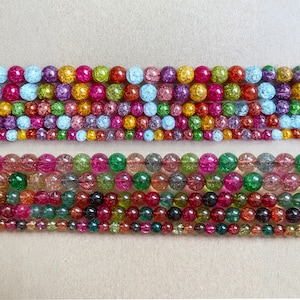 以下が含まれることがあります： カラフルでキラキラ光る丸いガラスビーズの糸。ビーズは列に並べられており、各列は異なる色の組み合わせになっています。ビーズは半透明で、斑点模様になっています。