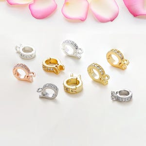 May include: Assortment of silver, gold, and rose gold tone metal clasps with clear crystal embellishments. Each clasp has a ring and a hook for attaching jewellery.