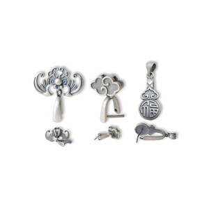 Può includere: Una collezione di componenti per gioielli in metallo argentato, tra cui ciondoli, chiusure e componenti per orecchini. I disegni presentano motivi ornamentali di ispirazione asiatica, come nuvole e forme floreali stilizzate. I pezzi sono esposti su sfondo bianco.