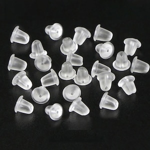 May include: A close-up of a group of clear plastic earring backs. The backs are small and round, with a small hole in the center. They are designed to be used with stud earrings.