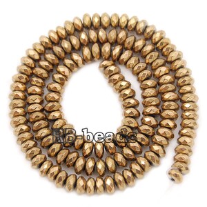 May include: A strand of gold-toned faceted beads. The beads are round and have a slightly elongated shape. The beads are strung on a clear thread.