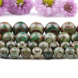 May include: A strand of green and brown agate beads with a swirling pattern. The beads are round and smooth.