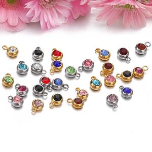May include: Assortment of colorful rhinestone charms with gold and silver settings. The charms feature a variety of colors, including red, blue, green, pink, and clear.