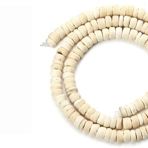 Peut inclure: Un brin de perles en os de couleur blanc cassé. Les perles sont rondes et ont une texture légèrement rugueuse.