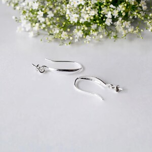 May include: A pair of silver earring hooks, each with a small loop at the top and a curved wire that forms a hook shape.
