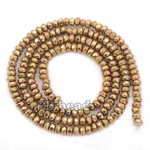 May include: A strand of gold-toned faceted hematite beads. The beads are round and have a slightly irregular shape. The beads are strung on a clear thread.