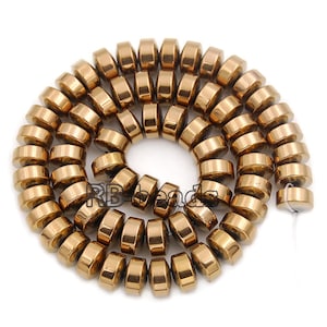 May include: A strand of gold-toned round hematite beads. The beads are smooth and have a metallic sheen.