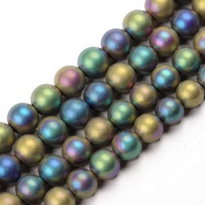 May include: Close-up of iridescent round beads in shades of green, blue, and gold. The beads are strung together, creating a textured surface. These beads are ideal for jewelry making and crafting projects.