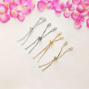 May include: Three silver and gold adjustable bracelet extender chains with clear crystal beads. The chains are made of a delicate box chain and have a sliding bead to adjust the length.