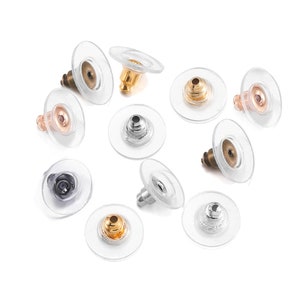 May include: Assortment of earring backs in various colors, including gold, silver, and black. The backs are made of metal and have a clear plastic backing.