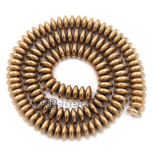 May include: A strand of round, flat, bronze-colored beads. The beads are arranged in a coil shape.