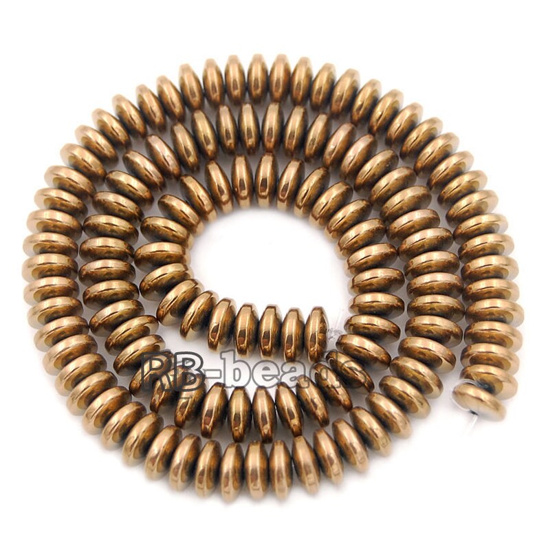 May include: A strand of round, flat, bronze-colored beads. The beads are arranged in a coil shape.
