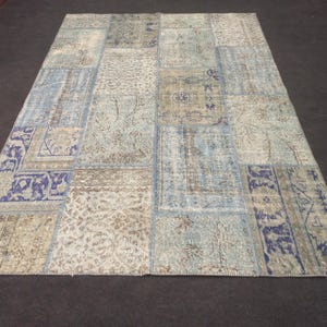 May include: A patchwork rug with a blue and beige color scheme. The rug is made of different pieces of fabric sewn together, creating a unique and interesting design.