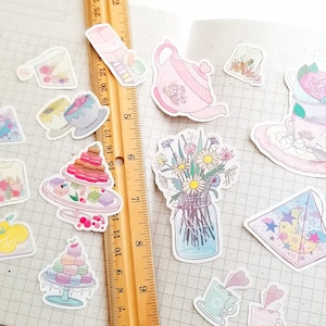 May include: A collection of pastel-colored stickers featuring a teapot, teacups, flowers, pastries, and other whimsical designs. The stickers are arranged on a gridded background.